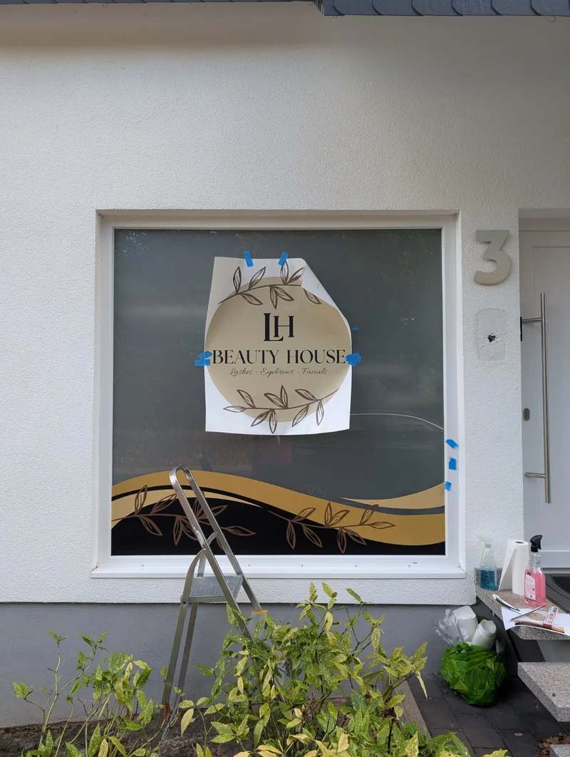 Montageschritt: Das Logo von LH Beauty House wird auf dem Fenster ausgerichtet
